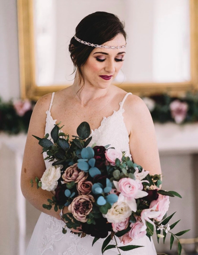 Bride in headpiece clutches flowers