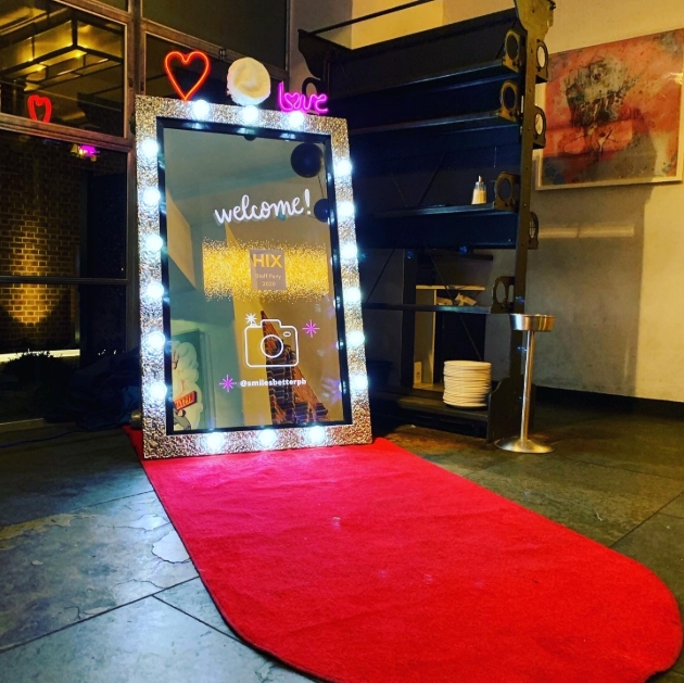 Illuminated magic mirror used to take photos of wedding guests rests on red carpet