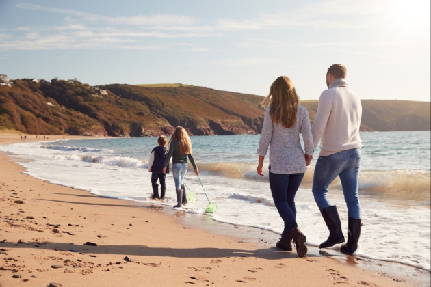 Family of four walk down the beach in boots