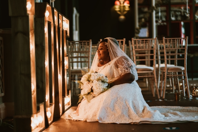 Bride sitting on the ground facing illuminated love sign