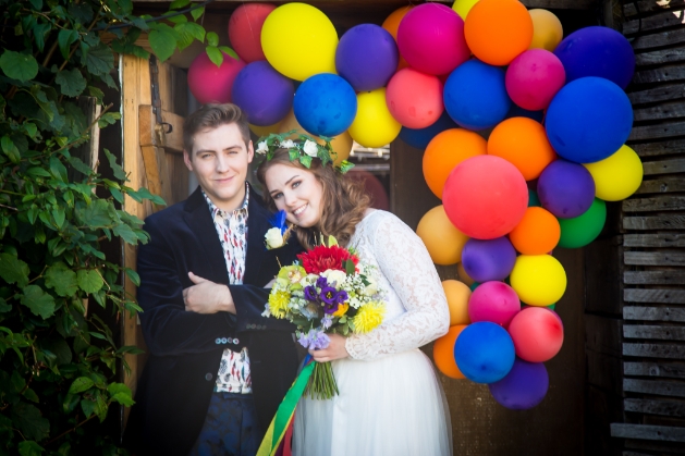 bride and broom with colourful balloon arch in the background