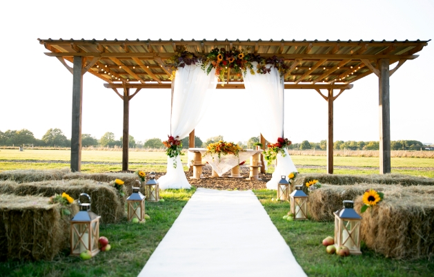 Outdoor wedding aisle with haybale seating and sunflower decoration