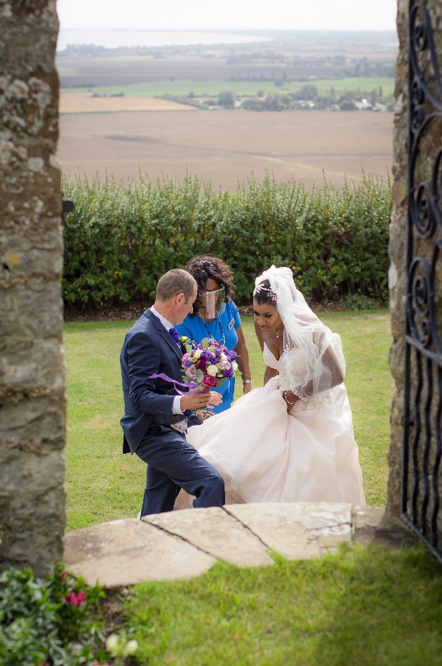 Blessing wears a visor for safety as she helps bride and groom into Lympne Castle