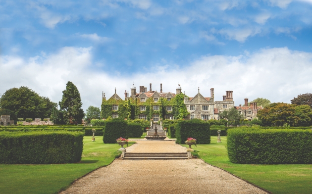 Eastwell Manor, grey historic building covered in ivy at the top of a graduate manicured garden