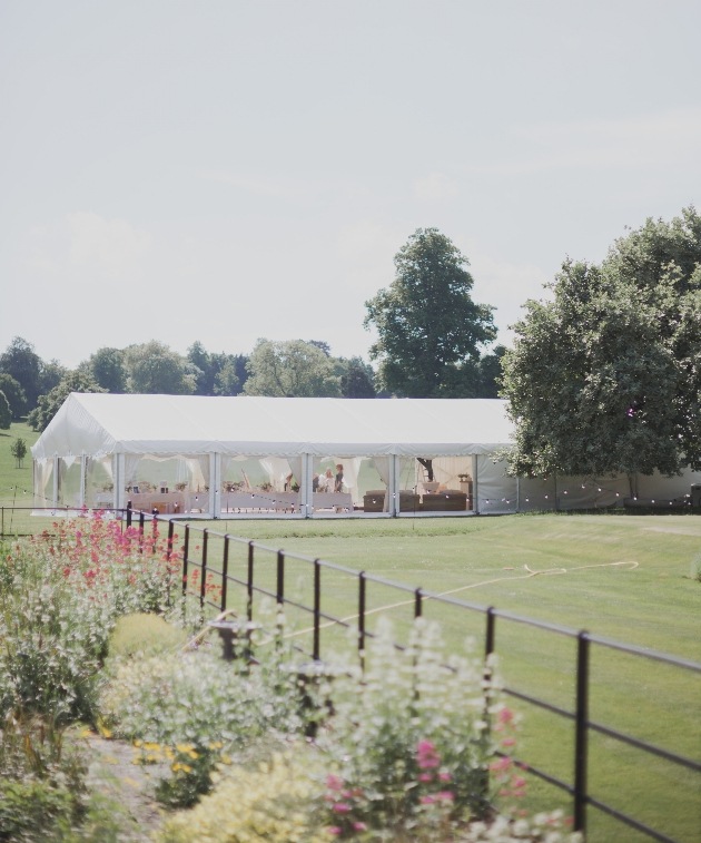 Marquee set up on open lawn with flowers in the foreground