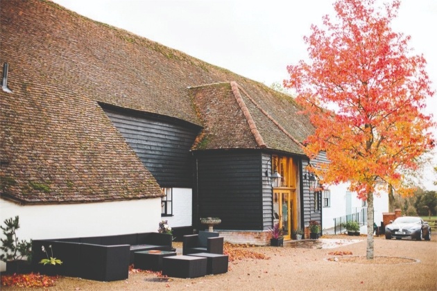 front of black and white barn with red tree