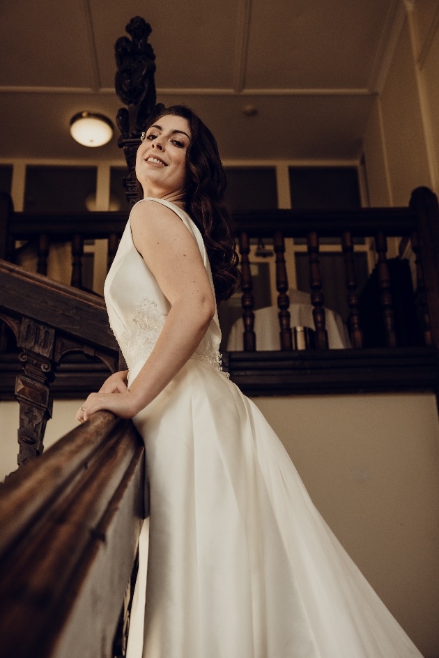 Bride on stairs at Broome Park with brunette hair in Hollywood waves tumbling down her back