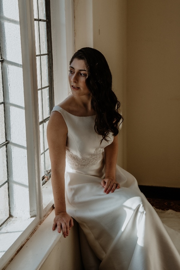 Bride sitting on windowsill looking out of the window