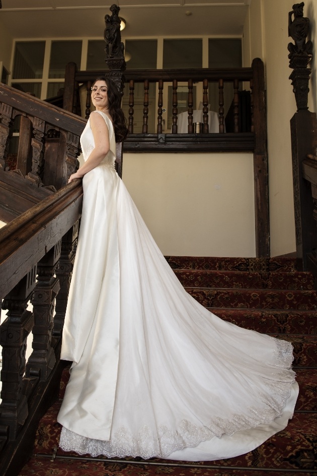 Looking up at bride on staircase with full view of stunning train. 