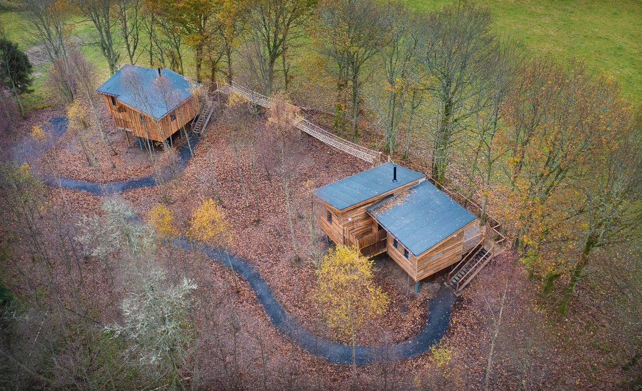 two treehouses low to ground surrounded by trees