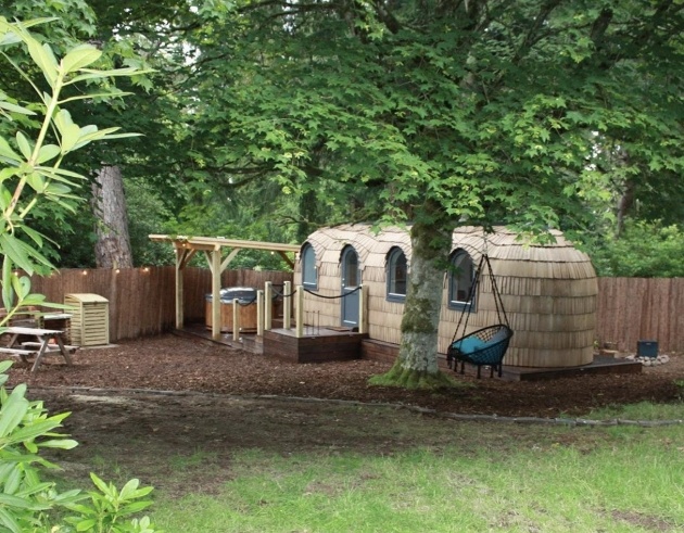 large pod in the woods with hot tub and fire pit