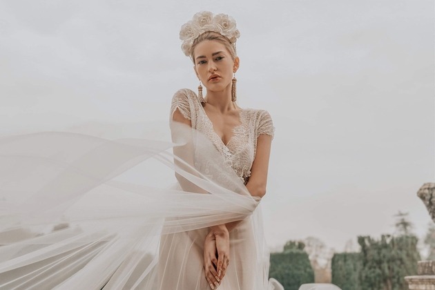 model wears ethereal gown with large floral headcrown