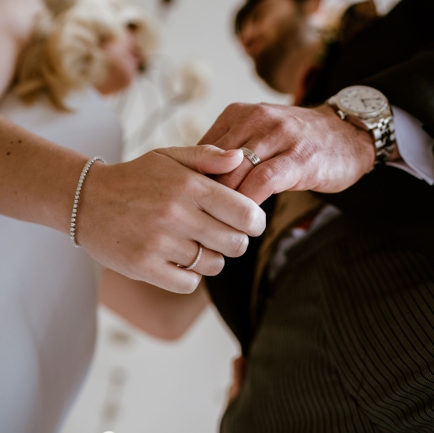 Bride and groom holding hands showing off their wedding rings