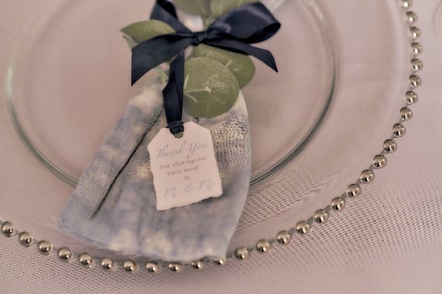 wedding favour pouch tied with blue ribbon sitting on clear plate