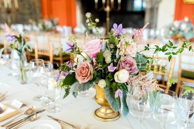 pink, dusky pink and purple table centres in a brass vase by Louise Roots