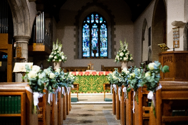 White pew end wedding flowers in a church by Louise Roots