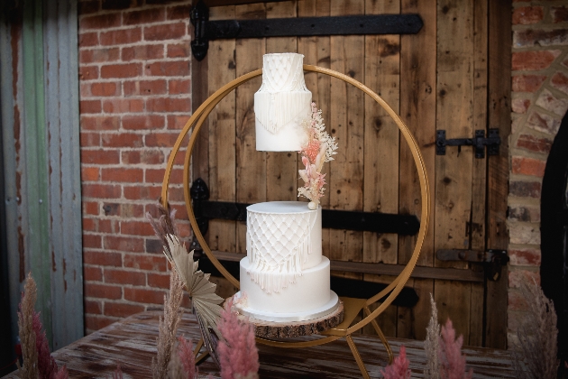 floating tier wedding cake decorated with dried flowers and displayed in a wooden hoop