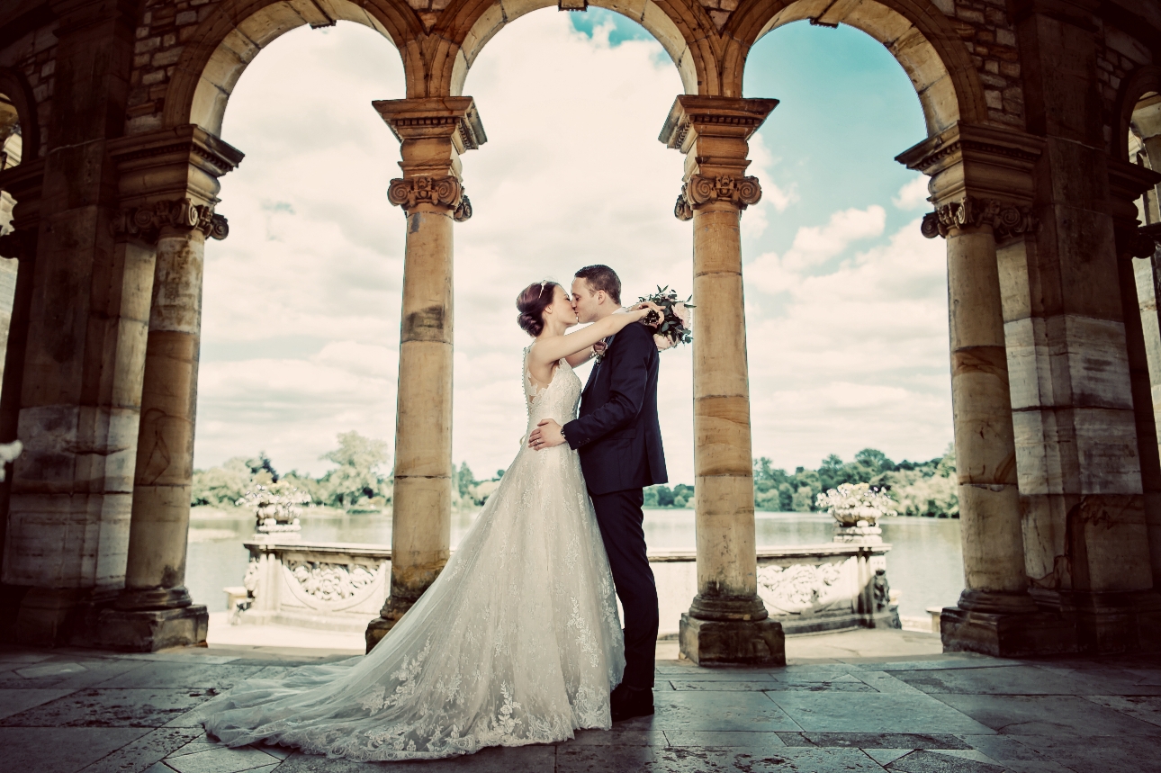 Bride and groom kissing in the italian gardens overlooking the lake at Hever Castle