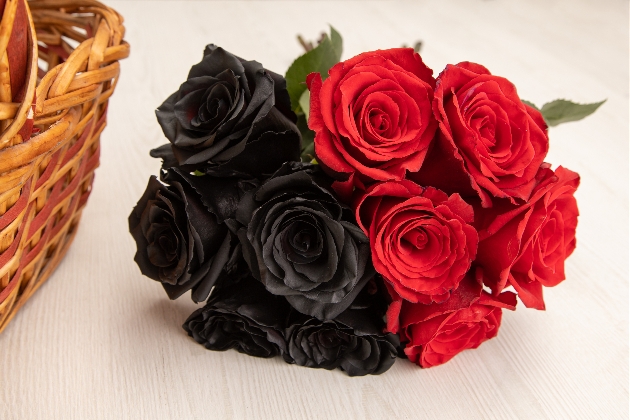 half black and half red rose bouquet on a table next to a wicker basket 