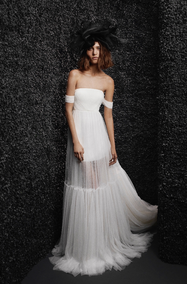 Model wearing a strapless A-line dress with short off-the-shoulder sleeves and a tulle skirt