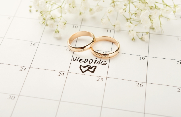 calendar with gypsophila and wedding rings on top. A wedding date is marked