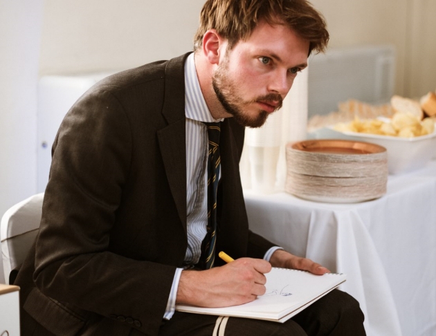 man in a suite sat down drawing at a wedding