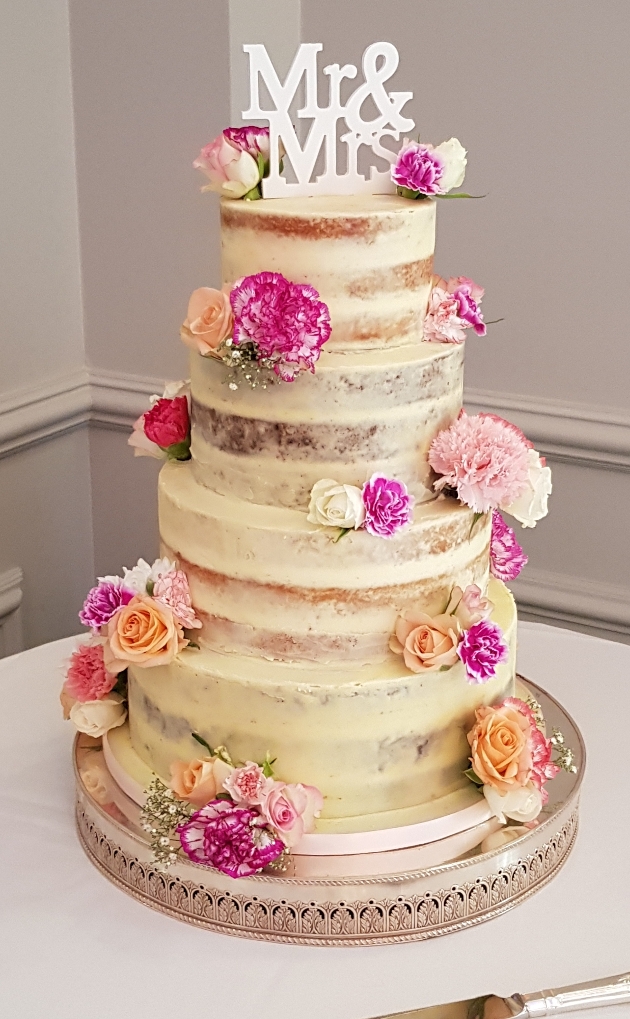 four tiered rustic cake with butter icing an flowers 