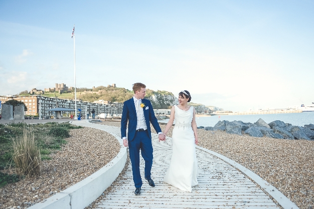 Bride and groom hand in hand on Dover seafront
