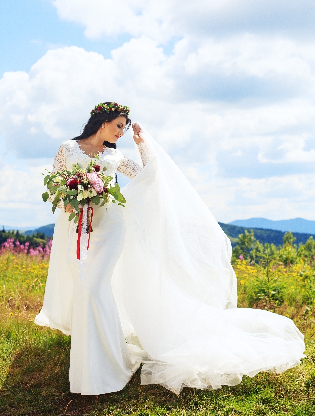 sunny day and a bride in a dress on a hillside holding bouquet