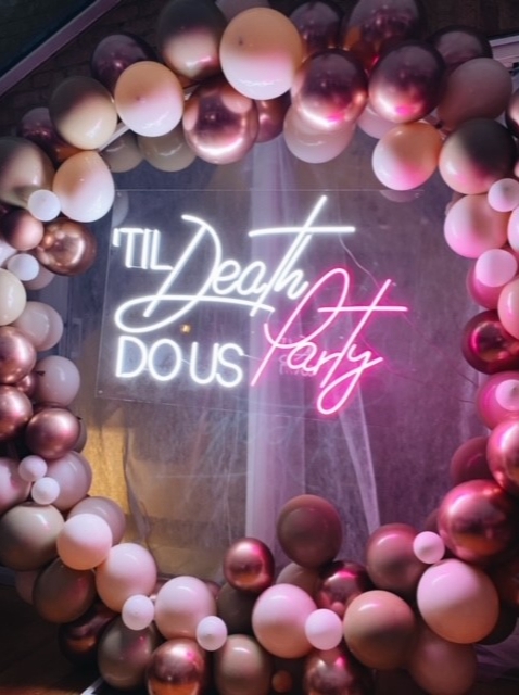 pink neon sign in a balloon arch