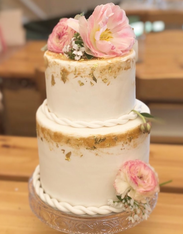 wedding cake with gold touches and pink flowers on top
