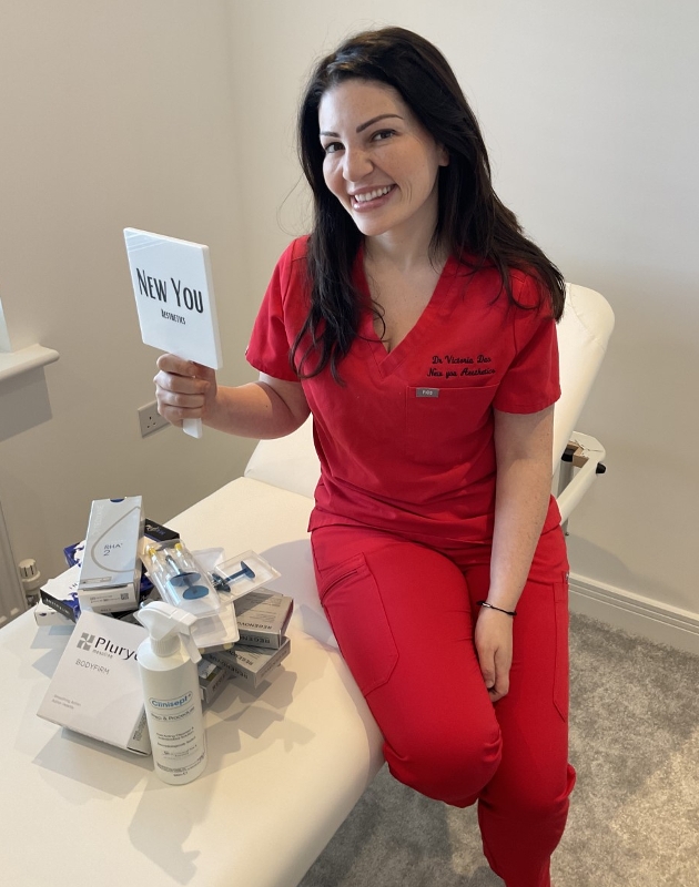 lady in red scrubs sitting on a bed with products