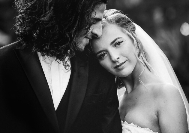 black and white photo of a bride resting her head on her groom's shoulder