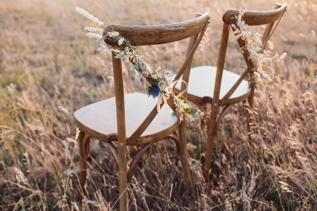 two wooden chairs in a cornfield decorated with dried flowers