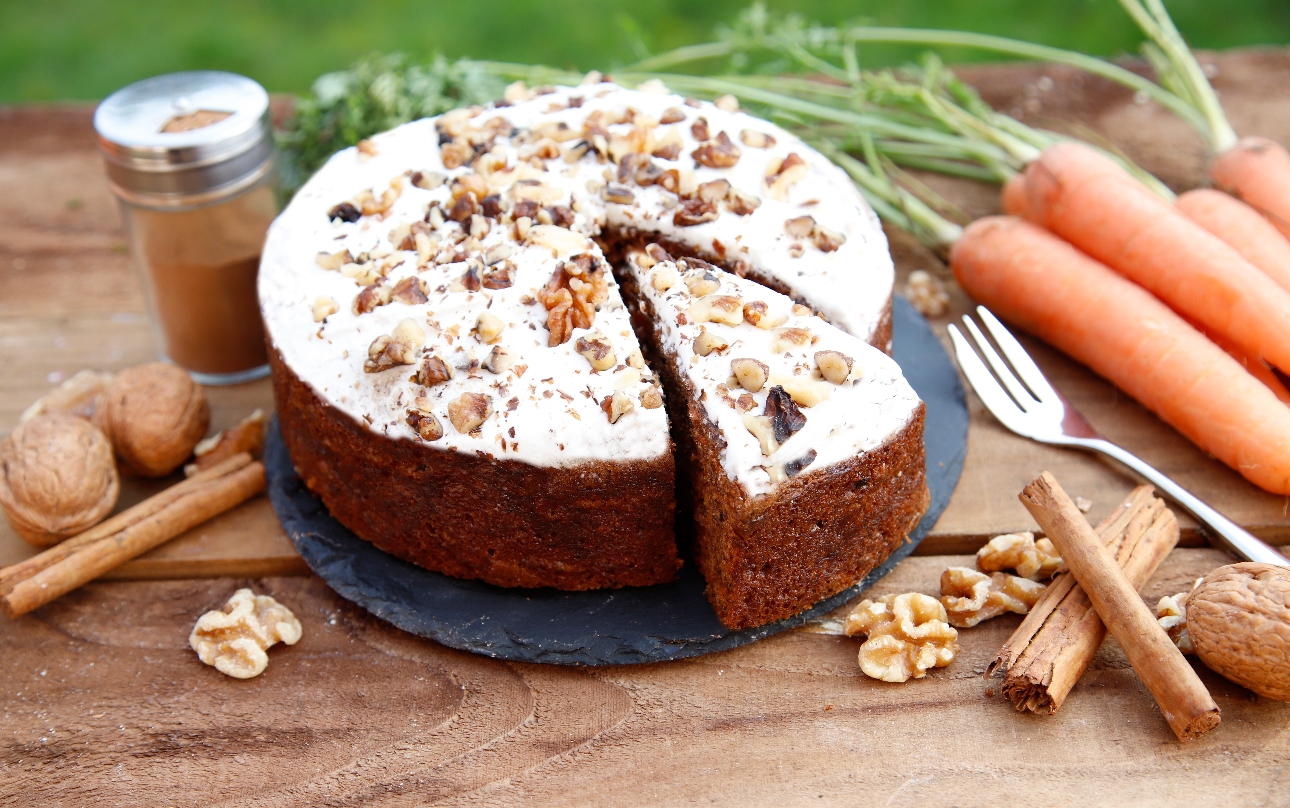 carrot cake on a wooden display with the ingredients laying around it