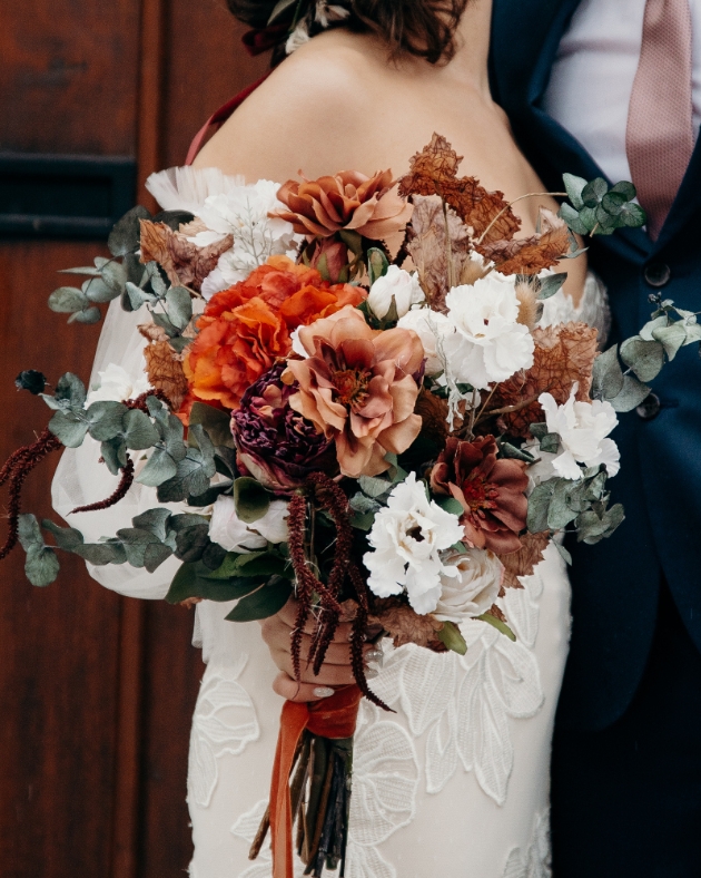 close up of faux flower bridal bouquet in orange and brown tones