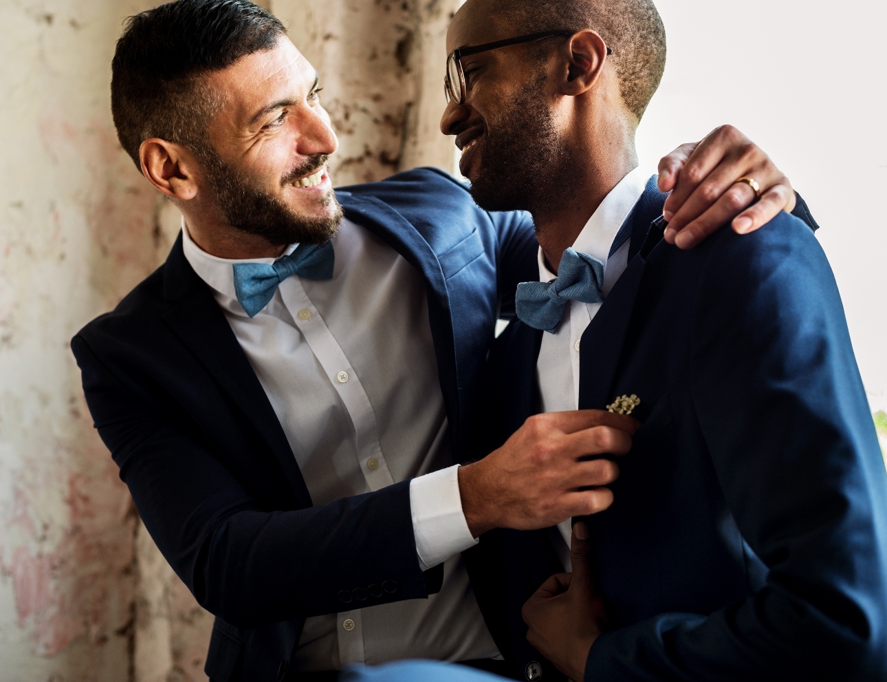 two men in blue wedding suits embracing