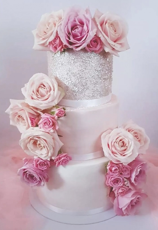 white cake with glitter top tier and pink roses.