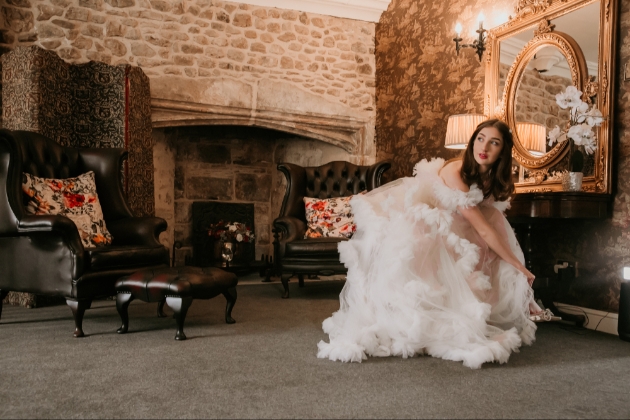 bride putting on her shoes sitting on brown leather sofas in Stone Court House