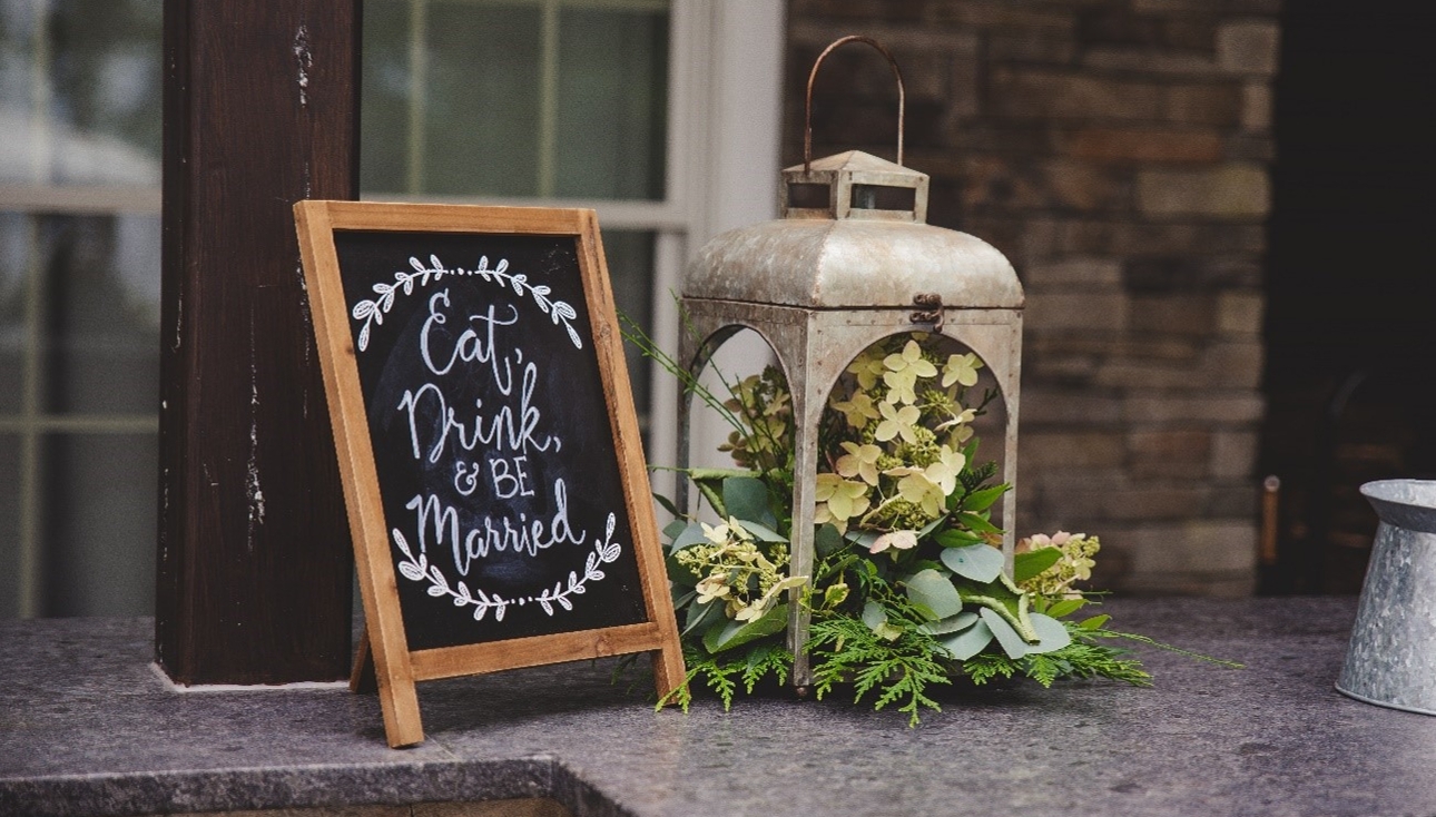 wooden 'eat drink and be married' sign on floor next to lantern