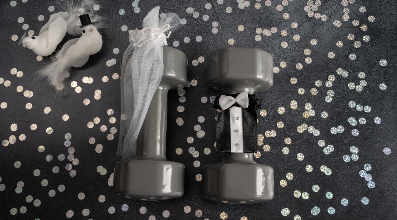 Two grey dumbells dressed as a bring and groom on a confetti background