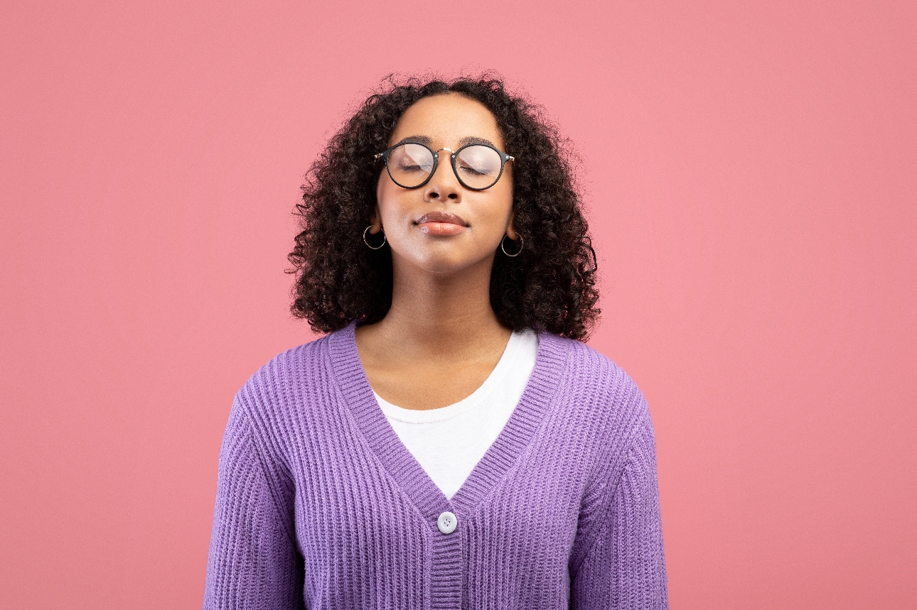 woman in purple jumper and glasses, with eyes shut happy