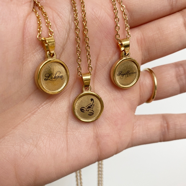 Three of Nikita's zodiac sign gold disc necklaces