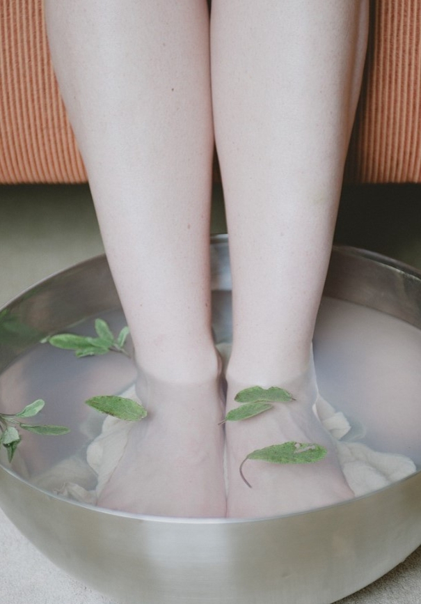 A foot spa with green leaves on a wooden backing. 