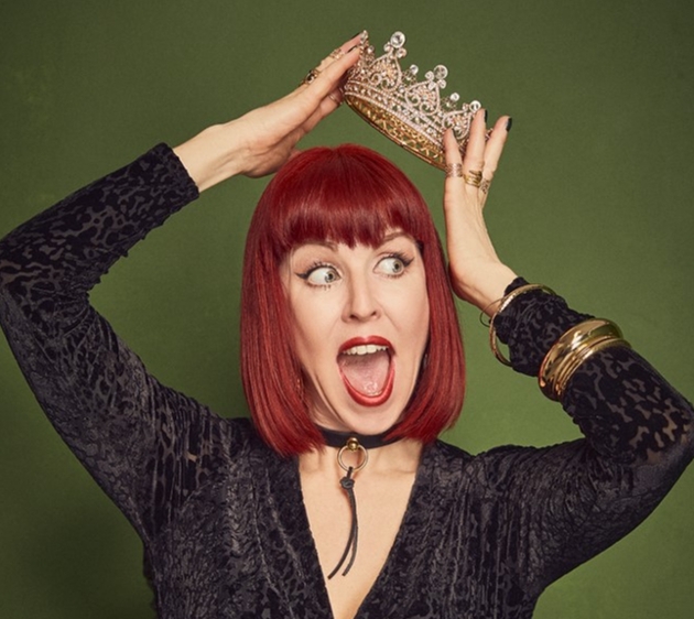 woman in black top short red hair popping a crown on her head