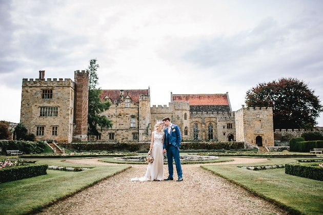 couple standing in front of stunning historic house with fountain