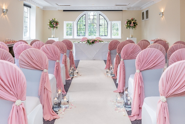 ceremony chairs covered in white covers with pink sashes looking at window