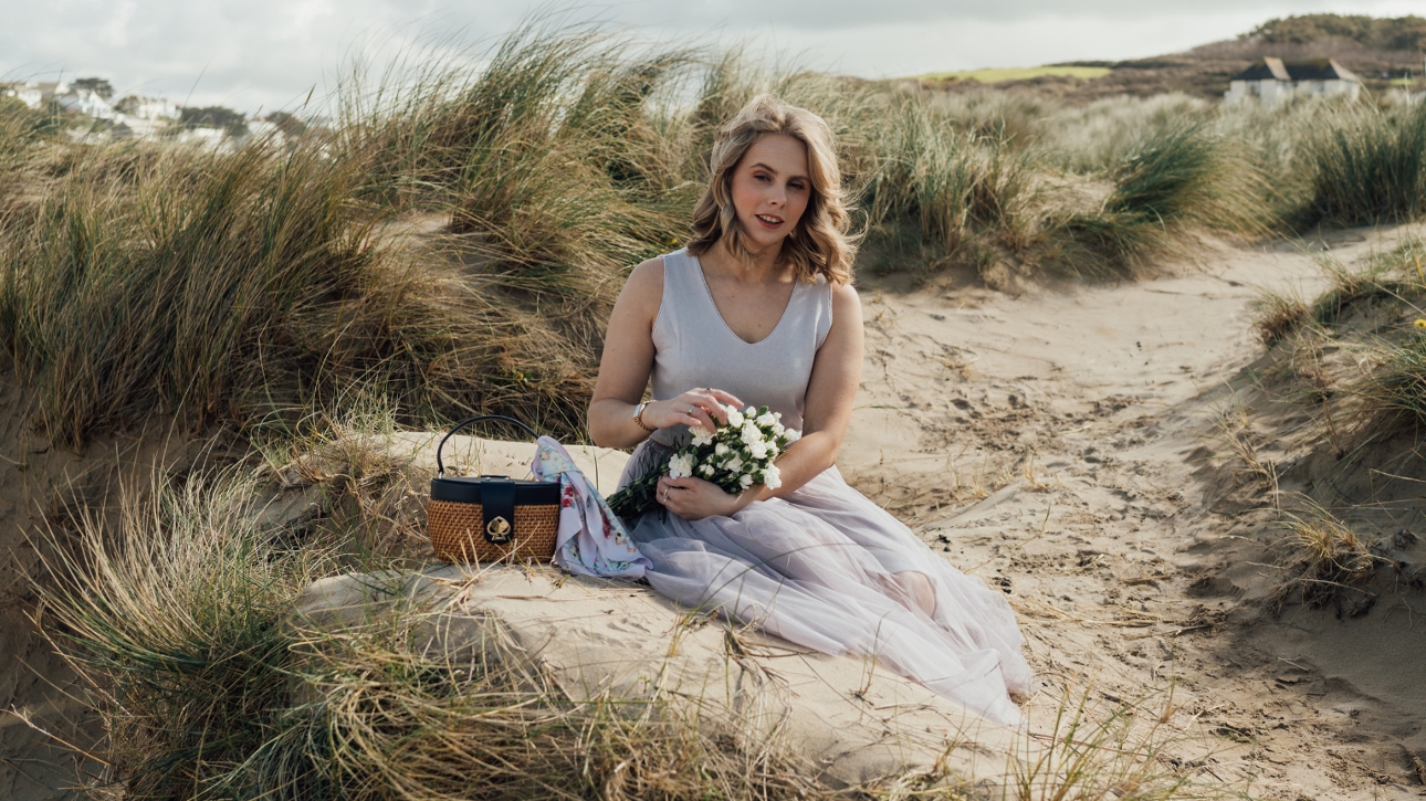 model in lilac dress sat on beach