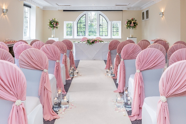 ceremony room white chairs with pink sashes