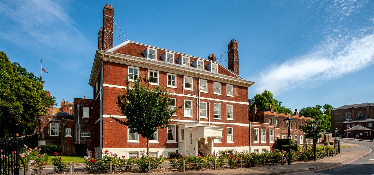 red brick building with white features and manicured front garden